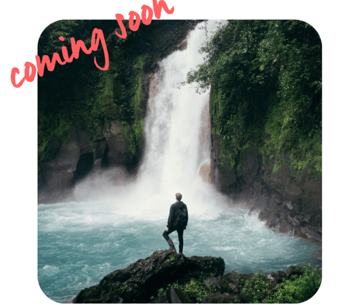 Person steht auf Felsen vor mächtigem Wasserfall in tropischer Umgebung mit türkisfarbenem Wasser und Schriftzug coming soon oben links.
