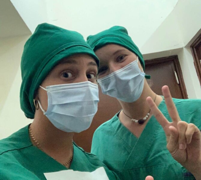 Medizinstudierende posieren in OP-Kleidung mit Peace-Zeichen im Krankenhaus vor Operation.