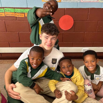 Freiwilliger spielt und lacht mit Schulkindern im Klassenzimmer während Sozialprojekt in Afrika
