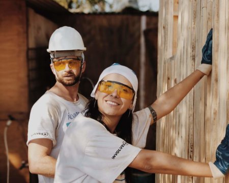 Zwei Leute renovieren in Arbeitskleidung eine Hütte