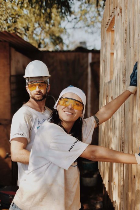Zwei Leute renovieren in Arbeitskleidung eine Hütte
