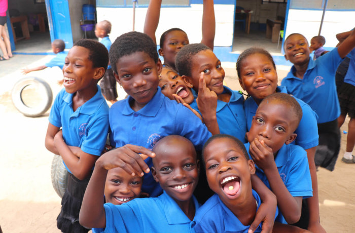Jungs mit blauer Schulkleidung lachen in die Kamera