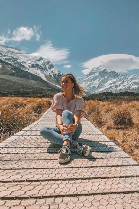 Mädchen sitzt auf einem Steg in mitten einer schönen Landschaft in Neuseeland
