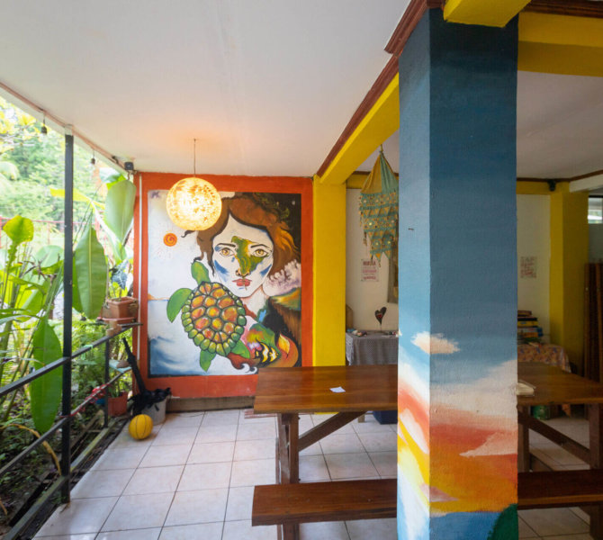 Bunter Gemeinschaftsbereich mit Wandmalerei und Holzbänken im wayers Volunteer House in Costa Rica.