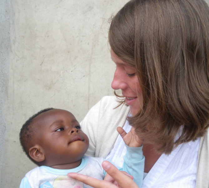 Freiwillige hält Baby im Arm während sozialem Einsatz in Ghana