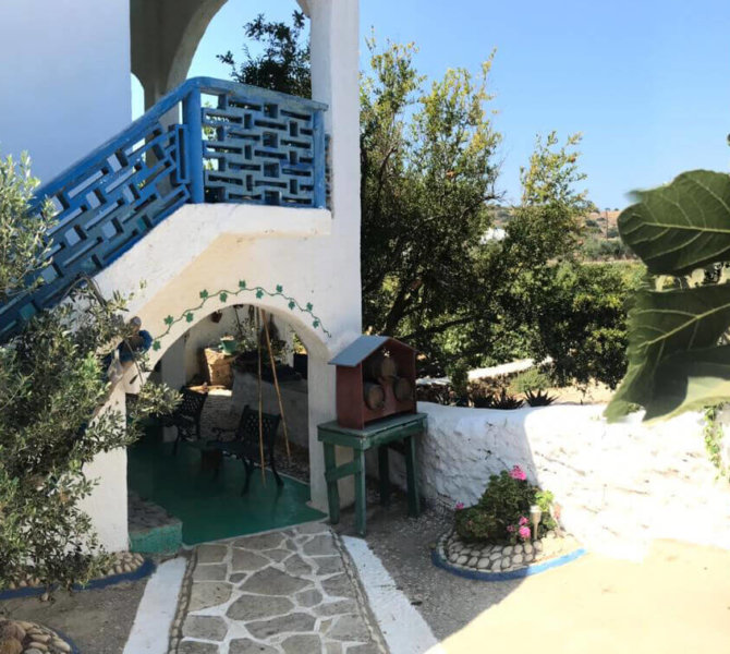 Charmantes weiß-blaues Haus auf griechischer Insel mit mediterranem Garten und traditionellem Flair unter strahlend blauem Himmel.