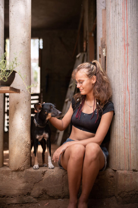 Freiwillige streichelt Hund und sitzt entspannt im Eingang einer Tierstation während Tierschutzprojekt in Mexiko