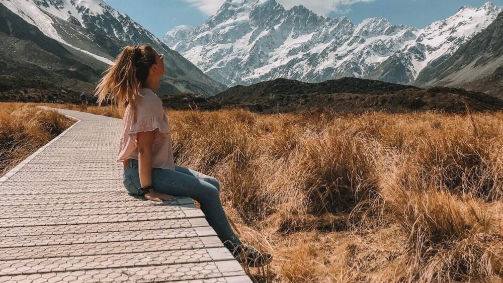 Mädchen sitzt inmitten einer schönen Landschaft in Neuseeland