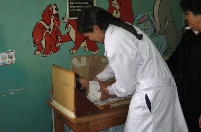 Ärztin untersucht Kleinkind in Holz-Messstation in Kinderklinik mit bunter Wandgestaltung