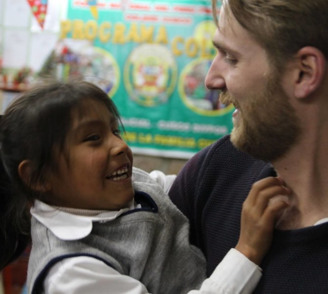 Freiwilliger lacht mit Kind während Pflegepraktikum in Peru in sozialem Projekt